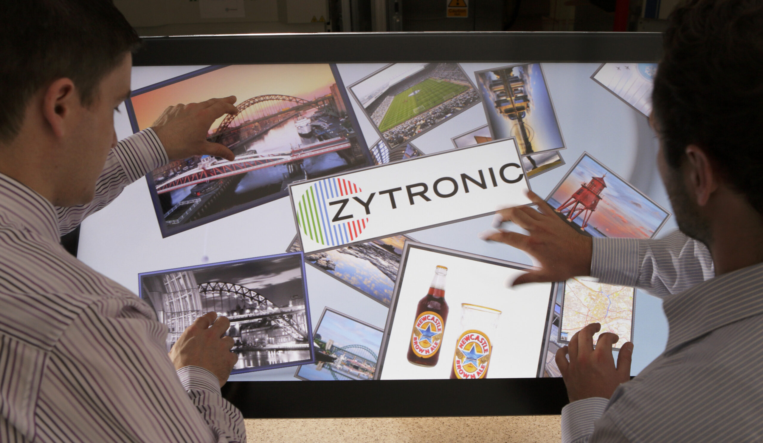 Two people using a Zytronic touchscreen with images of Newcastle