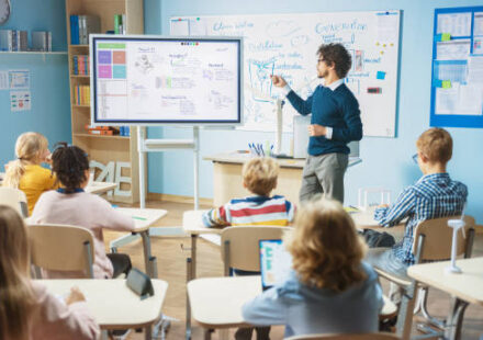 A teacher using a touchscreen board to teach children